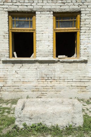 Téléchargez les photos : Fenêtres cassées dans un mur d'une maison endommagée - en image libre de droit