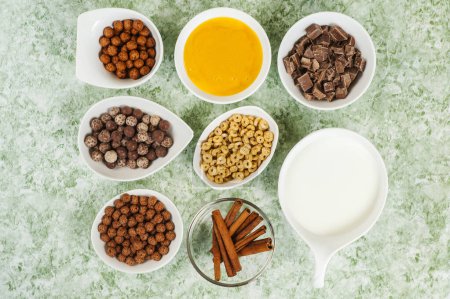 Photo for Top view of chocolate cereals in bowl and milk in jar and cinnamon and honey - Royalty Free Image