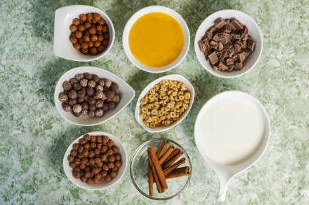 Foto de Vista superior de cereales de chocolate en tazón y leche en frasco y canela y miel - Imagen libre de derechos