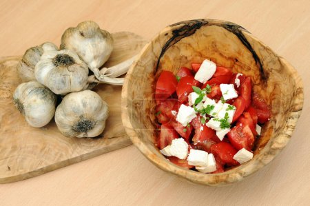 Foto de Tomates y ajo en plato de madera - Imagen libre de derechos