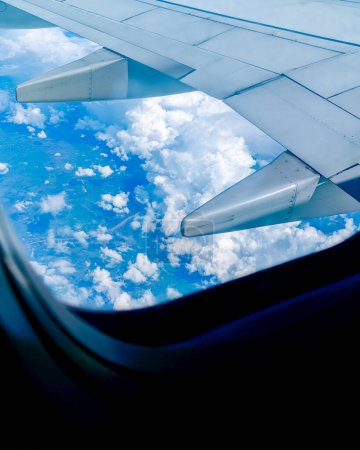 Téléchargez les photos : Vue aérienne d'un ciel bleu clair magnifique avec des nuages duveteux vus à travers une fenêtre d'avion. Concept de voyage - en image libre de droit