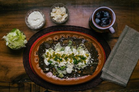 Photo for Enfrijoladas served in a clay dish. Typical Mexican food. Bean tacos with cream and cheese. - Royalty Free Image