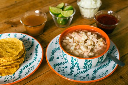 Téléchargez les photos : Pozole servi dans un plat profond, avec tostadas, salsa et légumes sur une table en bois. Nourriture mexicaine typique. - en image libre de droit