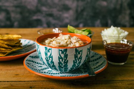 Téléchargez les photos : Pozole servi dans un plat profond, avec tostadas, salsa et légumes sur une table en bois. Nourriture mexicaine typique. - en image libre de droit