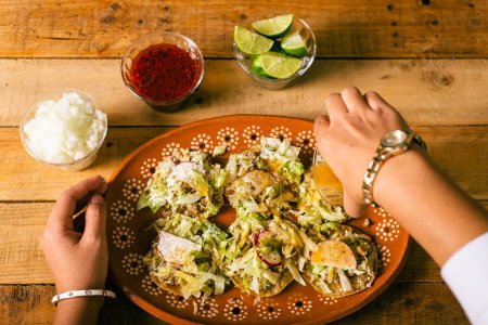 Photo for Woman's hands preparing Colima style sopitos on wooden table. Typical Mexican food. - Royalty Free Image