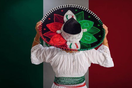 Photo for Woman shows Mexican hat with the colors of the Mexican flag. Mexican flag in background. - Royalty Free Image