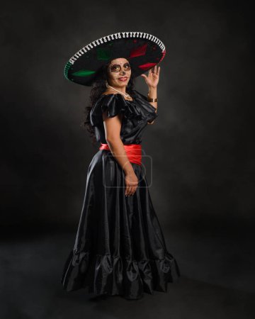 Foto de Catrina llevaba un sombrero de mariachi con los colores de la bandera mexicana. El día de la fiesta muerta. - Imagen libre de derechos