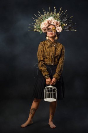 Foto de Retrato de mujer en maquillaje de cráneo de azúcar sosteniendo una jaula. Halloween y el día del maquillaje muerto. Retrato de Catrina. - Imagen libre de derechos