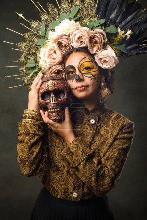 Foto de Retrato de mujer en maquillaje de cráneo de azúcar sosteniendo un cráneo. Halloween y el día del maquillaje muerto. Retrato de Catrina. - Imagen libre de derechos