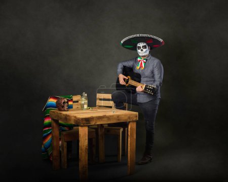 Photo for Catrin wearing mariachi hat and playing guitar in a bar. Day of the dead celebration. - Royalty Free Image