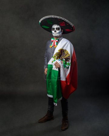 Portrait of catrin wearing charro hat and showing mexican flag. Day of the dead.