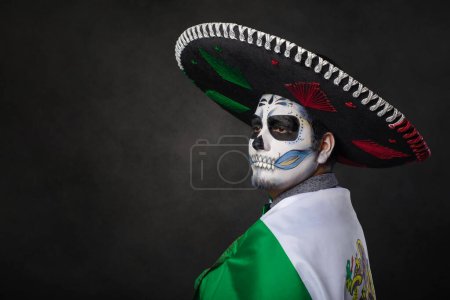 Photo for Portrait of catrin wearing charro hat and showing mexican flag. Day of the dead. - Royalty Free Image