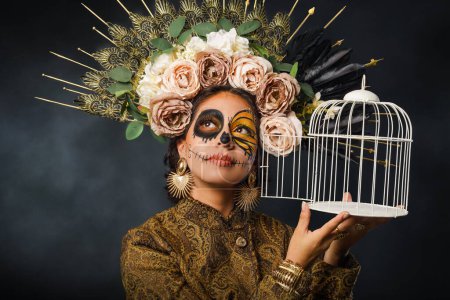 Foto de Retrato de mujer en maquillaje de cráneo de azúcar sosteniendo una jaula. Halloween y el día del maquillaje muerto. Retrato de Catrina. - Imagen libre de derechos