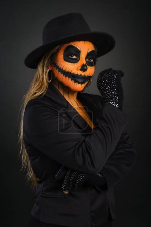 Woman made up as a pumpkin to celebrate Halloween looking at the camera.