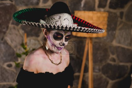 Photo for Woman made up as catrina wearing mariachi hat. Mexican woman celebrating day of the dead. Indoor portrait - Royalty Free Image