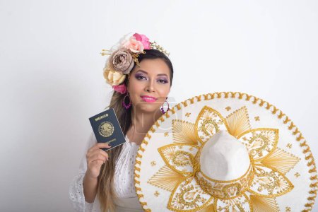 Photo for Mexican woman with flower headdress holding a mexican passport and mariachi hat. Woman with sombrero, white background. - Royalty Free Image