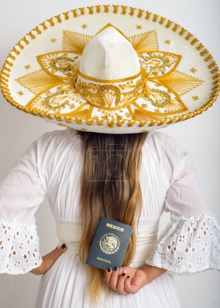 Photo for Mexican woman with charro hat holding a Mexican passport. View from behind her back. - Royalty Free Image