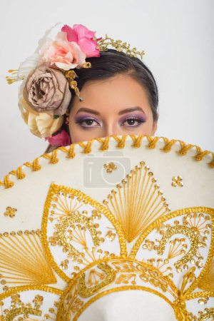 Photo for Mexican woman covering her face with mariachi hat. Woman with hat, white background. - Royalty Free Image