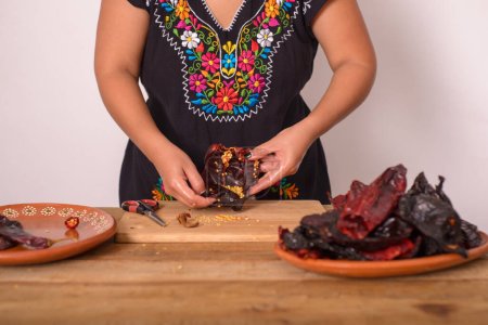 Woman opening ancho chili to remove the seeds. Ancho chili; condiment of Mexican cuisine.