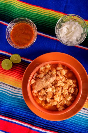 Téléchargez les photos : Pozole rouge servi dans un plat profond sur serape coloré. Nourriture mexicaine typique à base de maïs - en image libre de droit