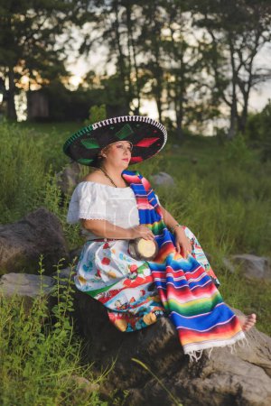 Photo for Woman with Mexican hat in rural scenery. Cinco de Mayo celebration in Mexico. - Royalty Free Image
