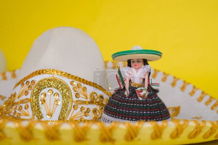 Photo for Doll representing the Mexican woman and mariachi hat on yellow background. - Royalty Free Image