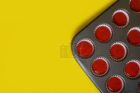 Tray with mix of red velvet cupcake ingredients ready to bake. Yellow background.