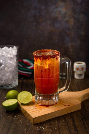 Michelada, typical mexican cocktail on a wooden table. Cocktail based on beer.