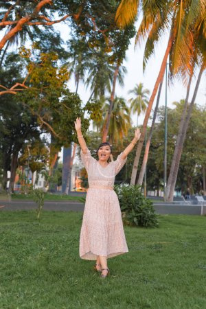 Woman with positive attitude raising her arms and shouting for joy in a public park.