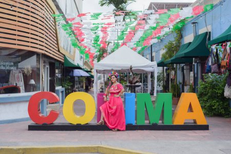 Photo for Mexican woman wearing traditional costume next to the giant letters of the city of Colima. Cinco de Mayo celebration. - Royalty Free Image