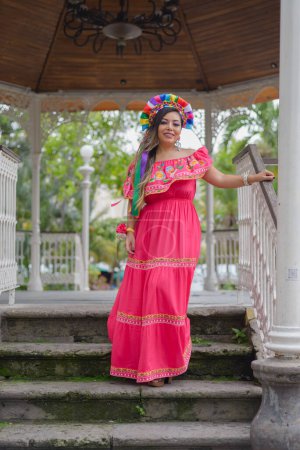 Mujer mexicana con vestido bordado y diadema de muñeca Lele. Retrato exterior. Celebración del Cinco de Mayo.