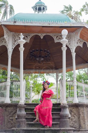 Mujer mexicana con vestido bordado y diadema de muñeca Lele. Retrato exterior. Celebración del Cinco de Mayo.