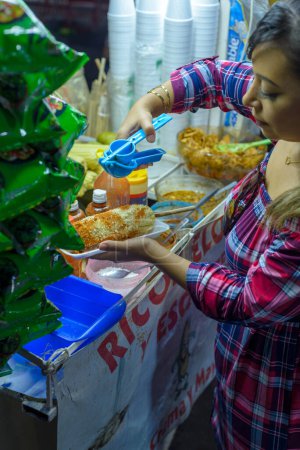 Mexican woman preparing a boiled corn, typical Mexican street food. Food stall. Elote.