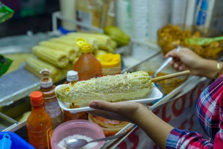 Mexican woman preparing a boiled corn, typical Mexican street food. Food stall. Elote.