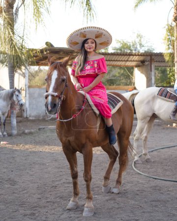Mexican woman wearing traditional dress and charro hat on horseback. Cinco de Mayo celebration.
