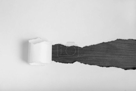 Téléchargez les photos : Papier blanc déchiré révélant sous un fond en bois noir. Espace pour le texte. - en image libre de droit