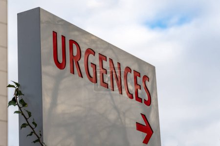 Signe avec le mot français "URGENCES" (signifiant "URGENCES") écrit en rouge indiquant la direction du service d'urgence d'un hôpital en France