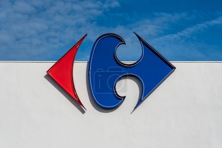 Téléchargez les photos : Anglet, France - 26 avril 2023 : Logo du groupe Carrefour sur un mur blanc et fond bleu ciel - en image libre de droit
