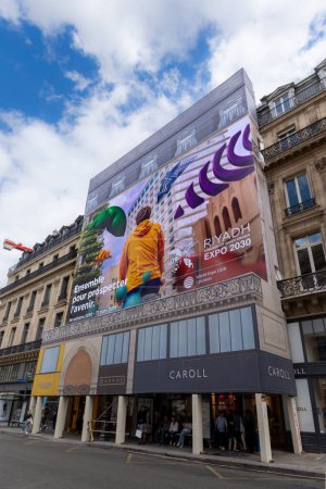 Foto de París, Francia - 1 de julio de 2023: Amplio cartel publicitario escrito en francés que promueve la candidatura de Riad para la exposición mundial 2030 que cubre las obras de renovación de un edificio parisino - Imagen libre de derechos