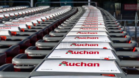 Téléchargez les photos : Gap, France - August 6, 2023: Close-up of a row of many shopping carts branded with the logo of an Auchan store, a French company and multinational retail group - en image libre de droit