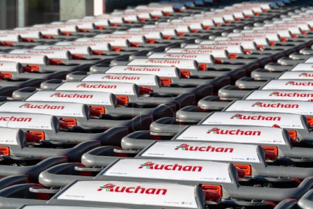 Téléchargez les photos : Gap, France - August 6, 2023: Close-up of a row of many shopping carts branded with the logo of an Auchan store, a French company and multinational retail group - en image libre de droit