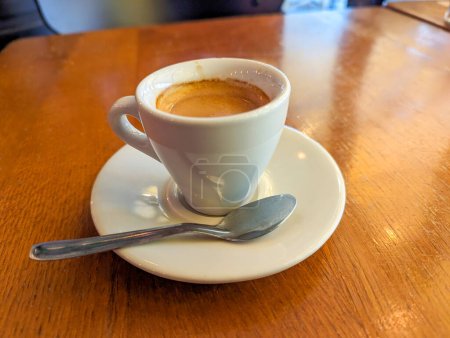 Foto de Café expresso tradicional servido en una taza blanca sobre la mesa de un bistró parisino - Imagen libre de derechos