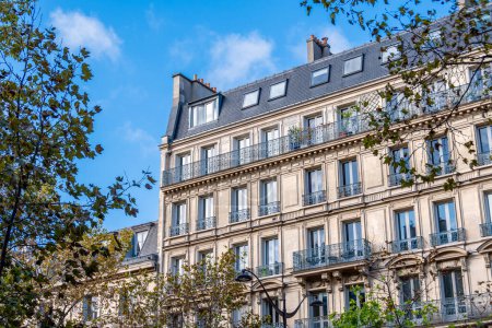 Photo pour Façade d'un immeuble résidentiel de style classique à Paris situé sur une avenue bordée d'arbres. Concept de marché immobilier résidentiel pour les logements anciens en France - image libre de droit