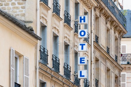 Schild mit dem Wort "HOTEL" in hellen Großbuchstaben an der Fassade eines Gebäudes in Paris, Frankreich