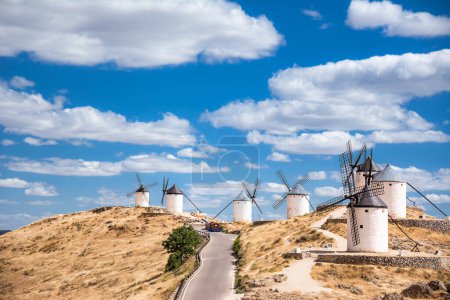 Foto de Serie de molinos de Consuegra en la colina con cielo azul y nubes blancas (España) - Imagen libre de derechos