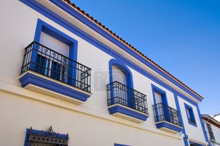 Foto de Fachada de una casa con ventanas enmarcadas azules, típica de España - Imagen libre de derechos