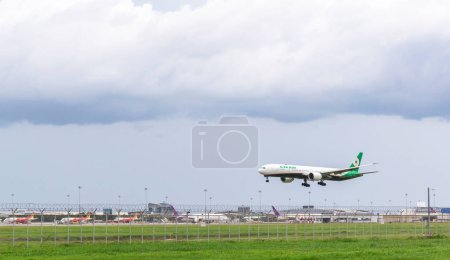 Photo for Samut Prakan, Thailand: July 30, 2023: Evaair aircraft is landing and preparing to take off with an air traffic control tower background at Suvarnabhumi international airport. - Royalty Free Image