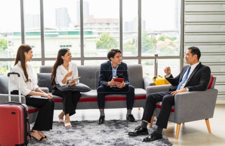 Foto de Grupo de empresarios masculinos y femeninos se sentaron y charlaron en el salón de invitados antes de salir a visitar el extranjero. - Imagen libre de derechos