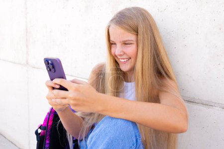 Photo for Smiling teenage girl using mobile phone outdoors - Royalty Free Image