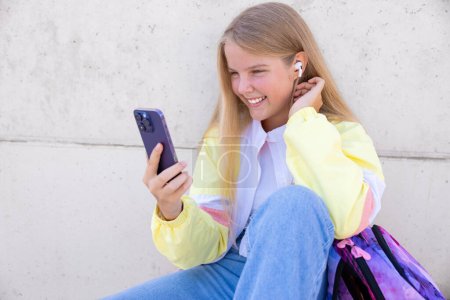 Photo for Teenage girl using mobile phone and listening to music - Royalty Free Image